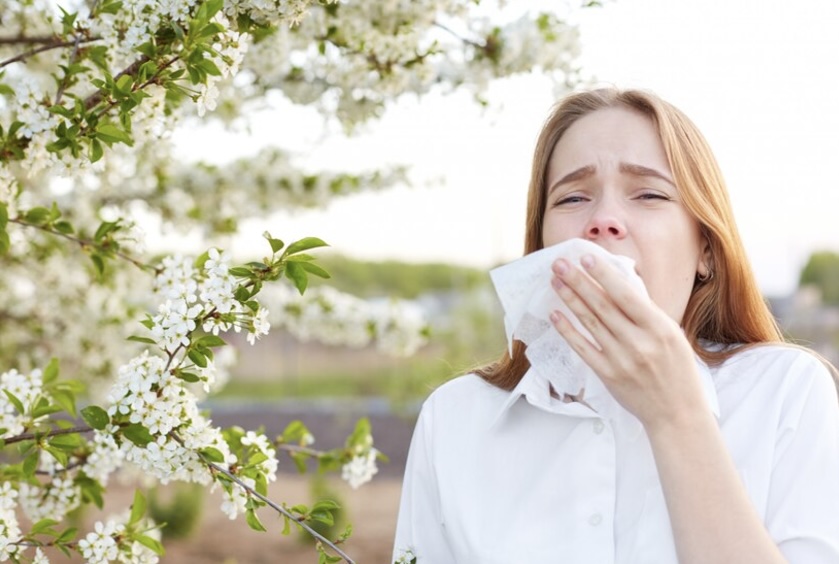 Woman sneezing due to pollen allergy